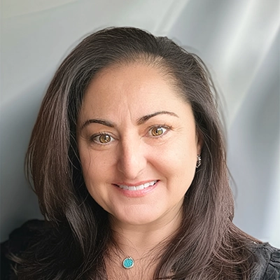 Dentist Suzanne Cohen Smiling In Front Of Silver Background